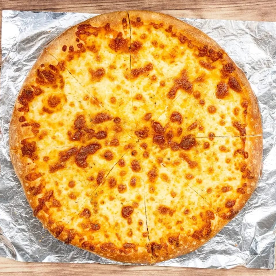 Bravo Pizza's cheese pizza, cut into slices, on aluminum foil and a wooden surface.