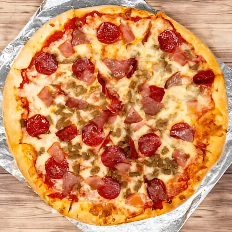 Bravo Pizza's meat lover's pizza, topped with pepperoni, sausage, and ham, on a wooden table.