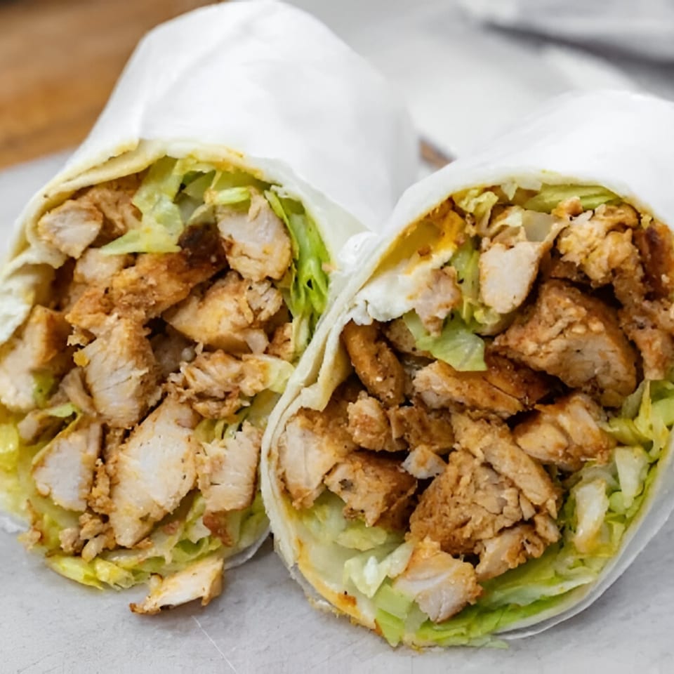 Two chicken wraps, cut in half, filled with grilled chicken pieces and fresh green lettuce.